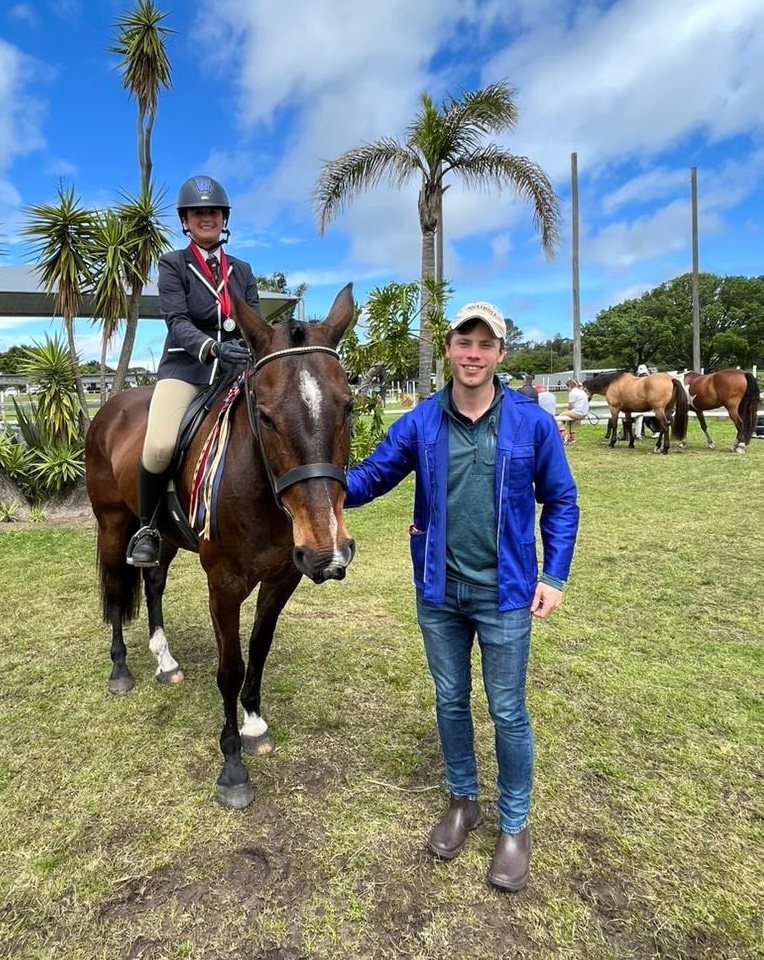 Kirstin on her horse at a show, with Michael standing beside them